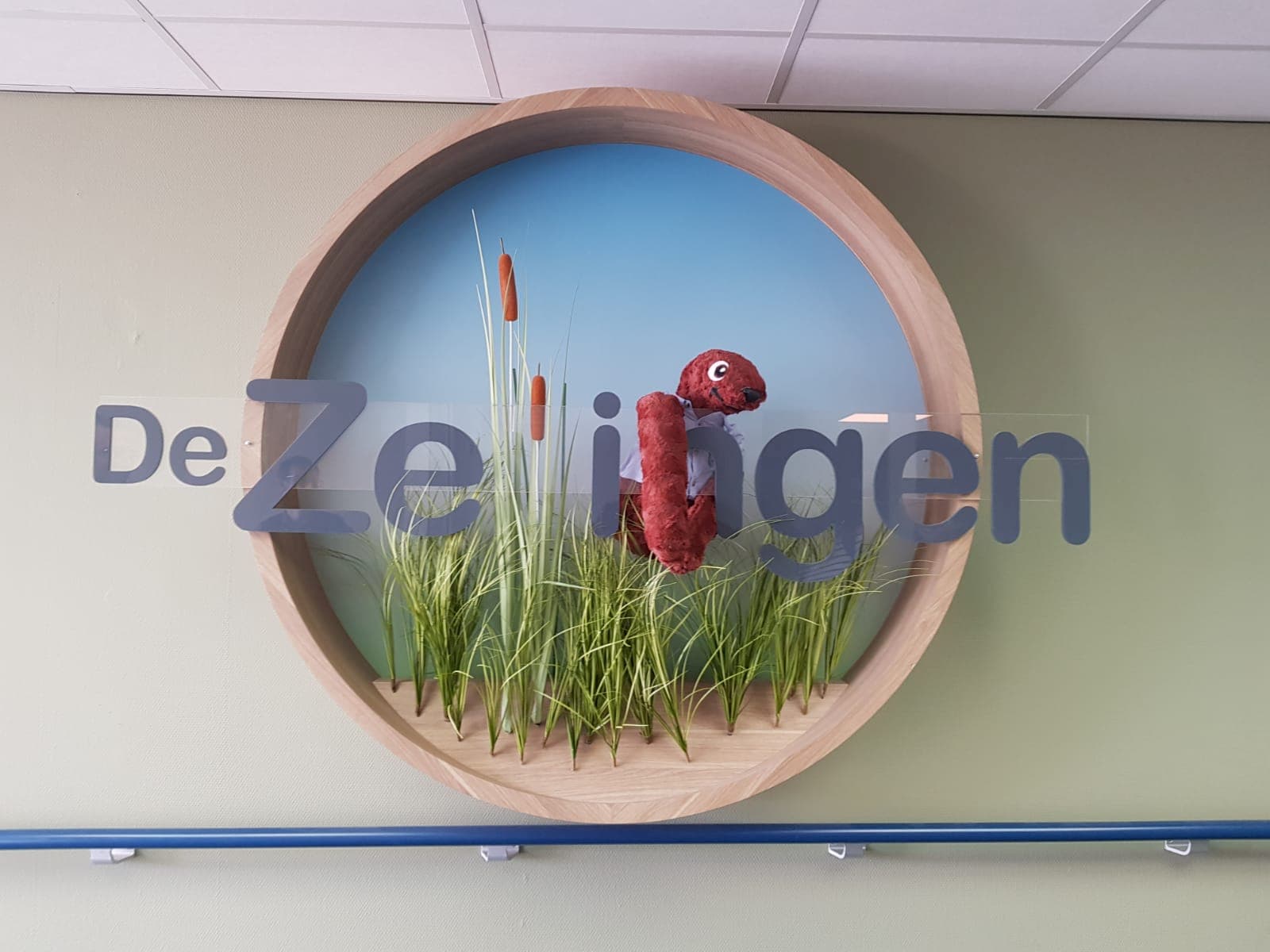 Sid hugging the big physical logo of the Zellingen located in the main hall.